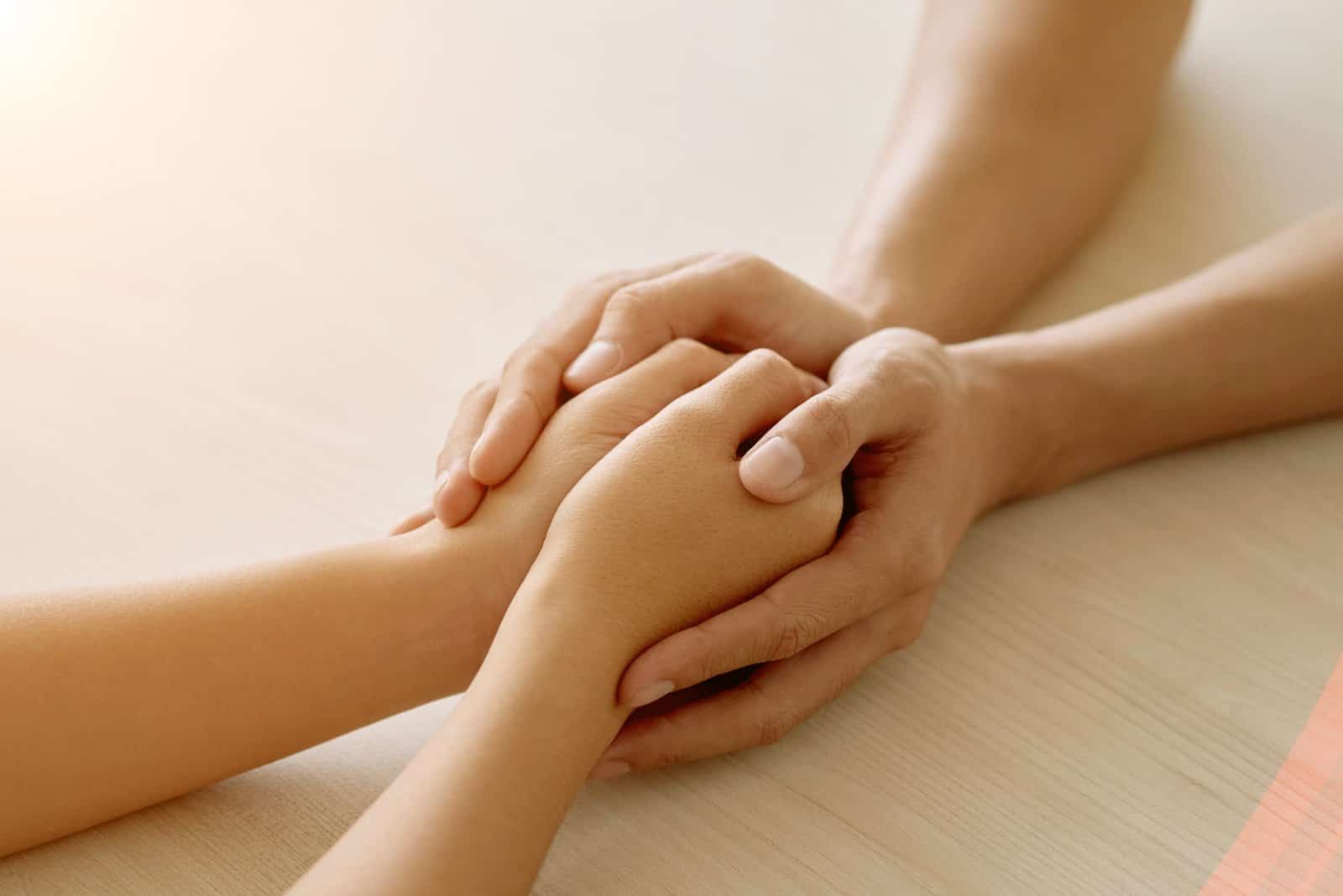 Manos reconfortándose mutuamente, reflejando la validación emocional y el apoyo de tu psicóloga en Marbella.
