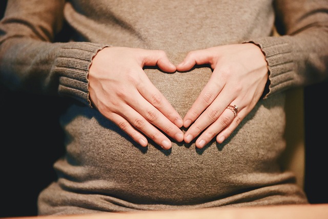 Manos formando un corazón sobre el vientre, reflejan la psicología perinatal y posparto.